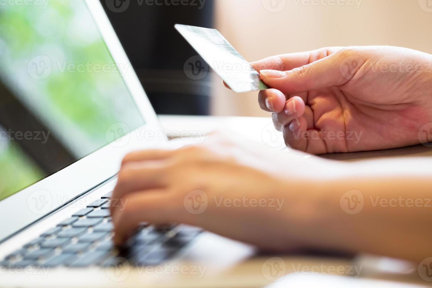 Mujer con tarjeta de crédito en la computadora portátil por concepto de compras en línea foto