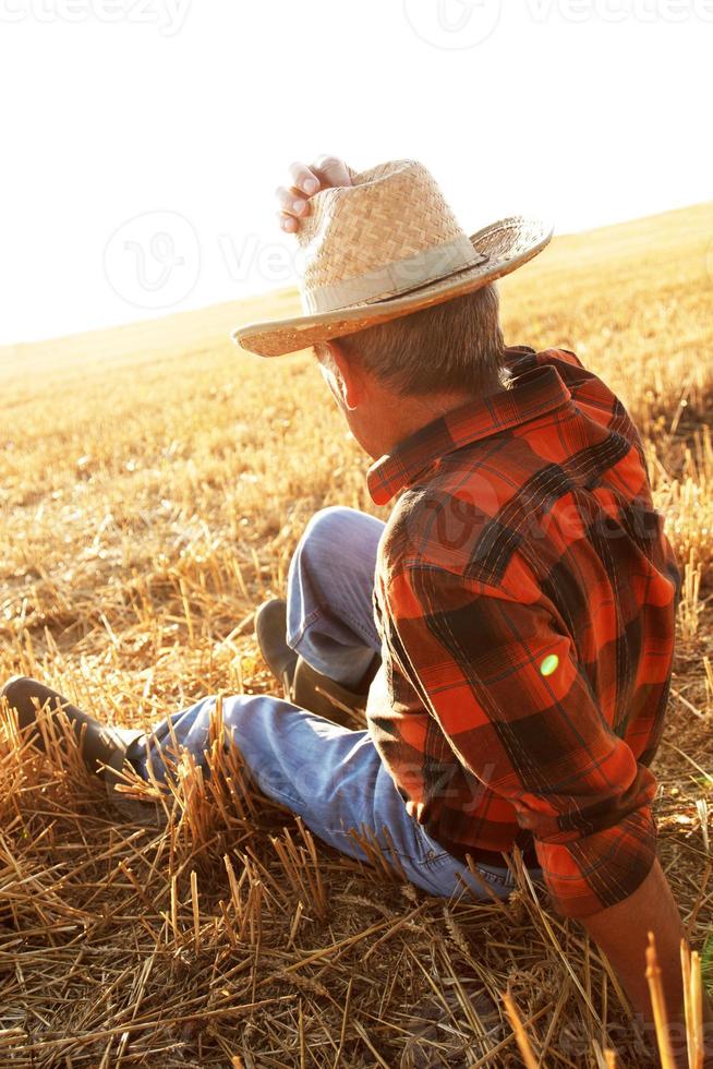 Senior farmer sitting on field photo
