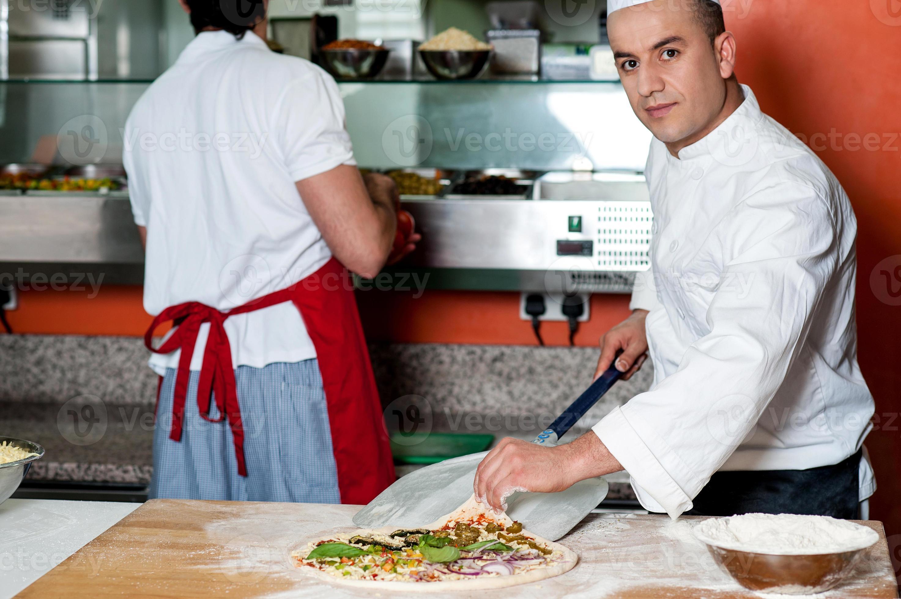 Chef giving last touches to vegetable pizza photo