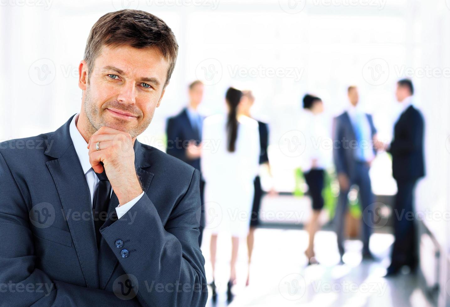 Mature smiling manager followed by young business people photo
