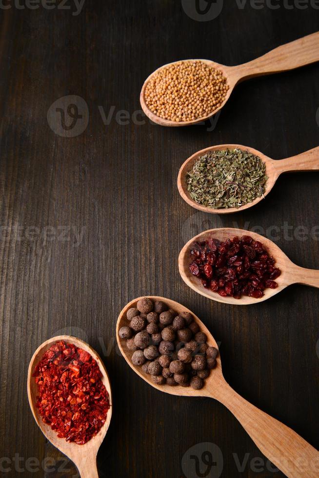 Different spices in spoons on wooden background photo