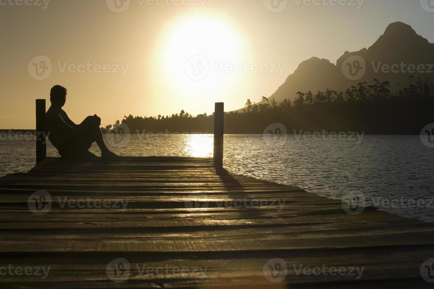 Man Sitting On Dock By Lake photo