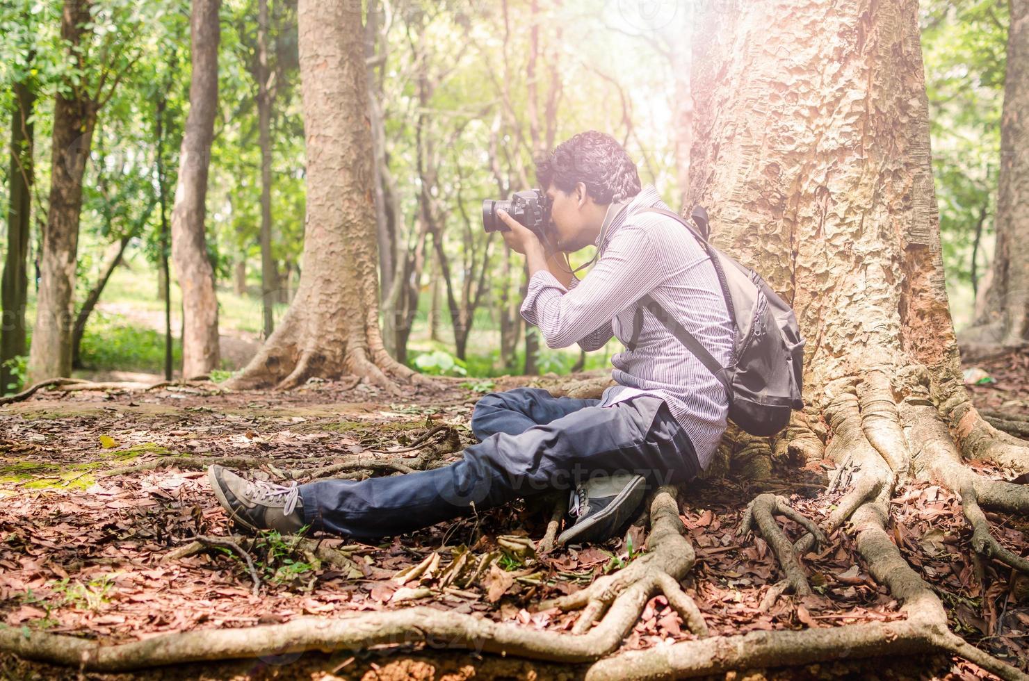 Photographer taking photos sitting under a big tree