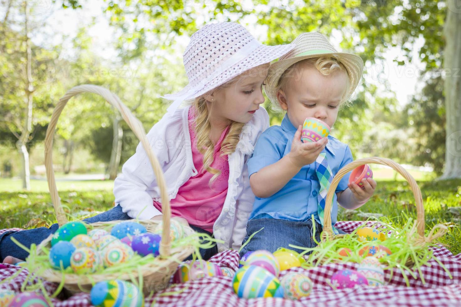 lindo joven hermano y hermana disfrutando de sus huevos de pascua afuera foto