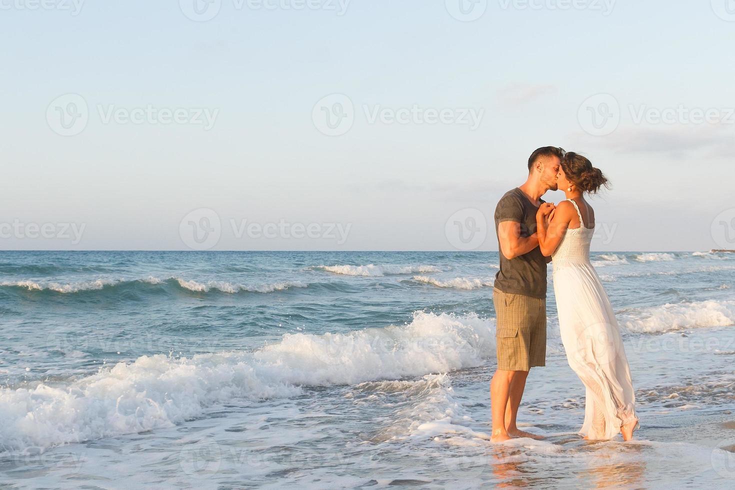 joven pareja disfruta caminando en una playa nublada al anochecer foto