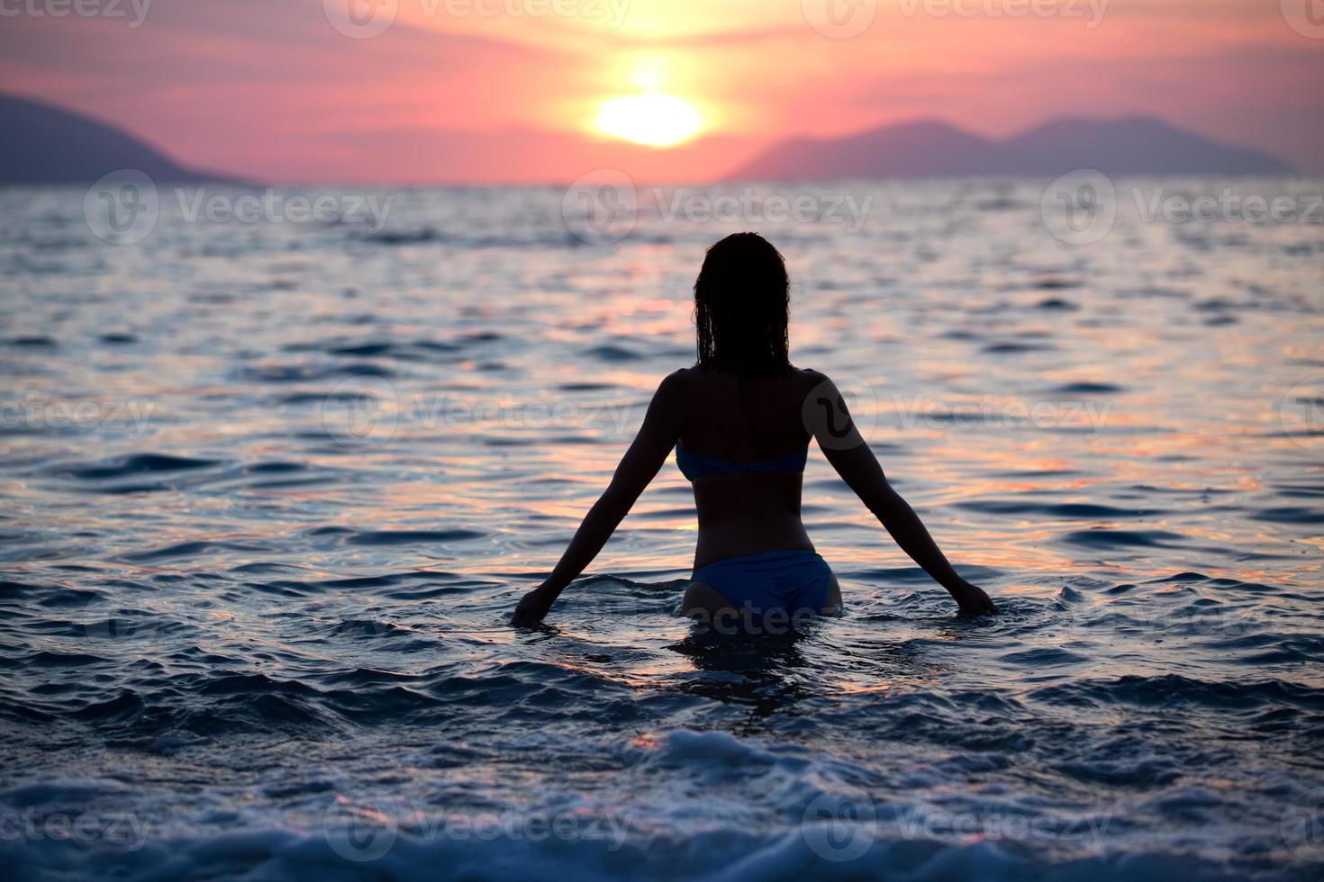 Gorgeous fit woman silhouette swimming in sunset.Free woman enjoying sunset. photo