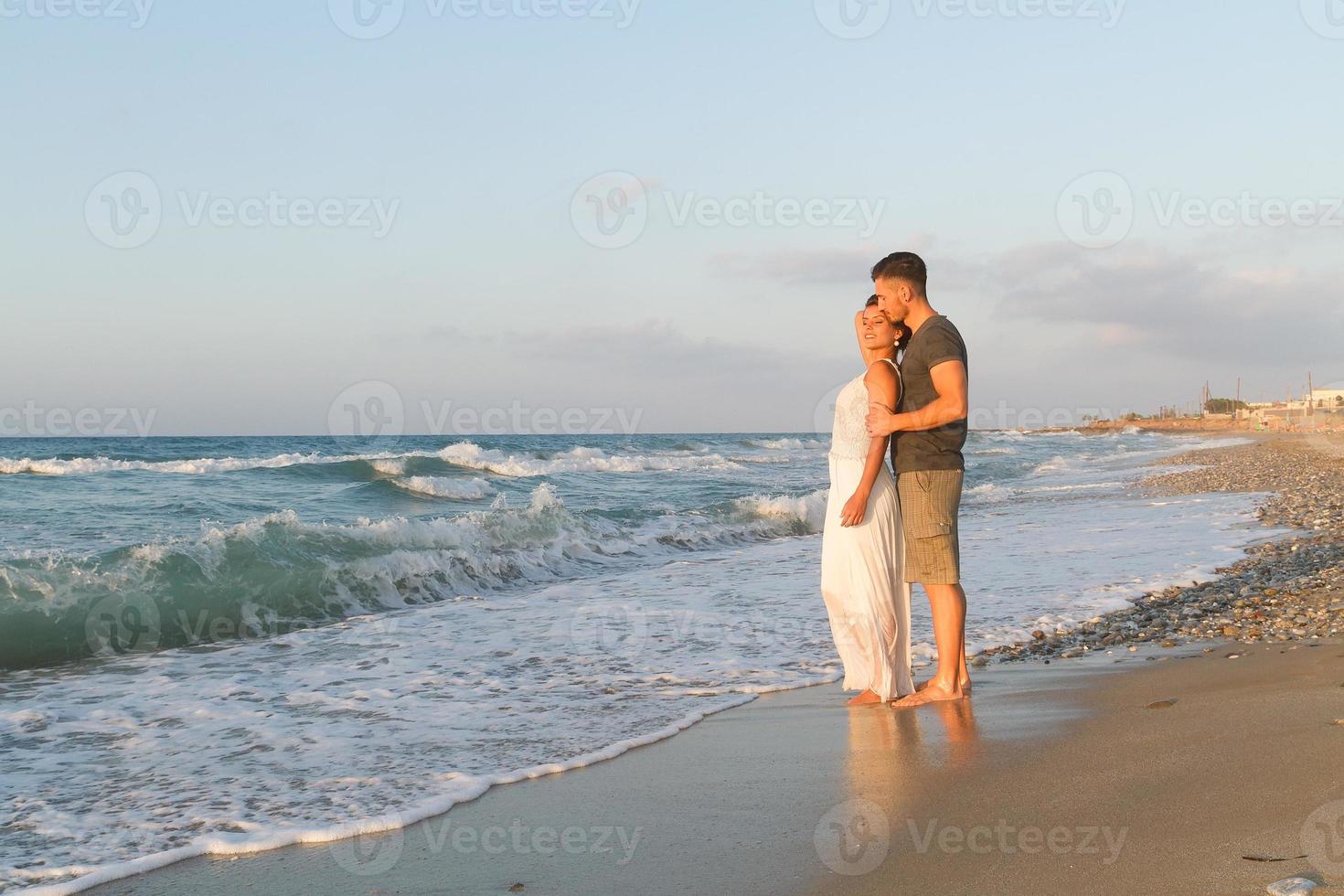 joven pareja disfruta caminando en una playa nublada al anochecer foto