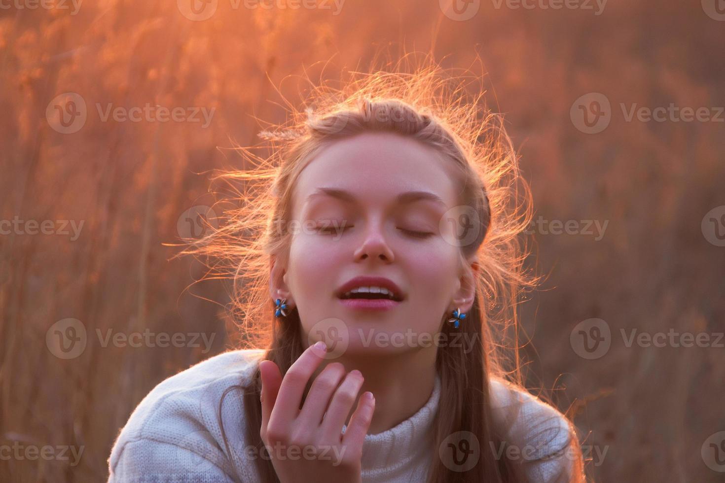 Beautiful young blonde woman daydreams at sunset photo