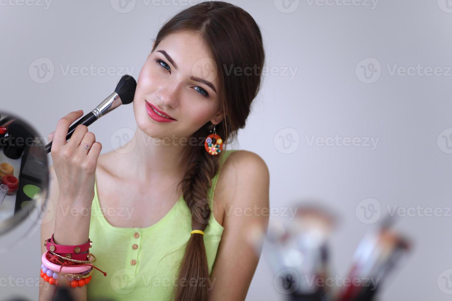 Young beautiful woman making make-up near mirror photo