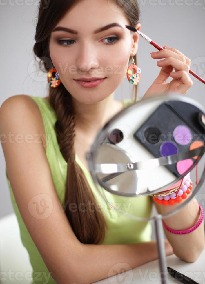 Young beautiful woman making make-up near mirror,sitting at photo