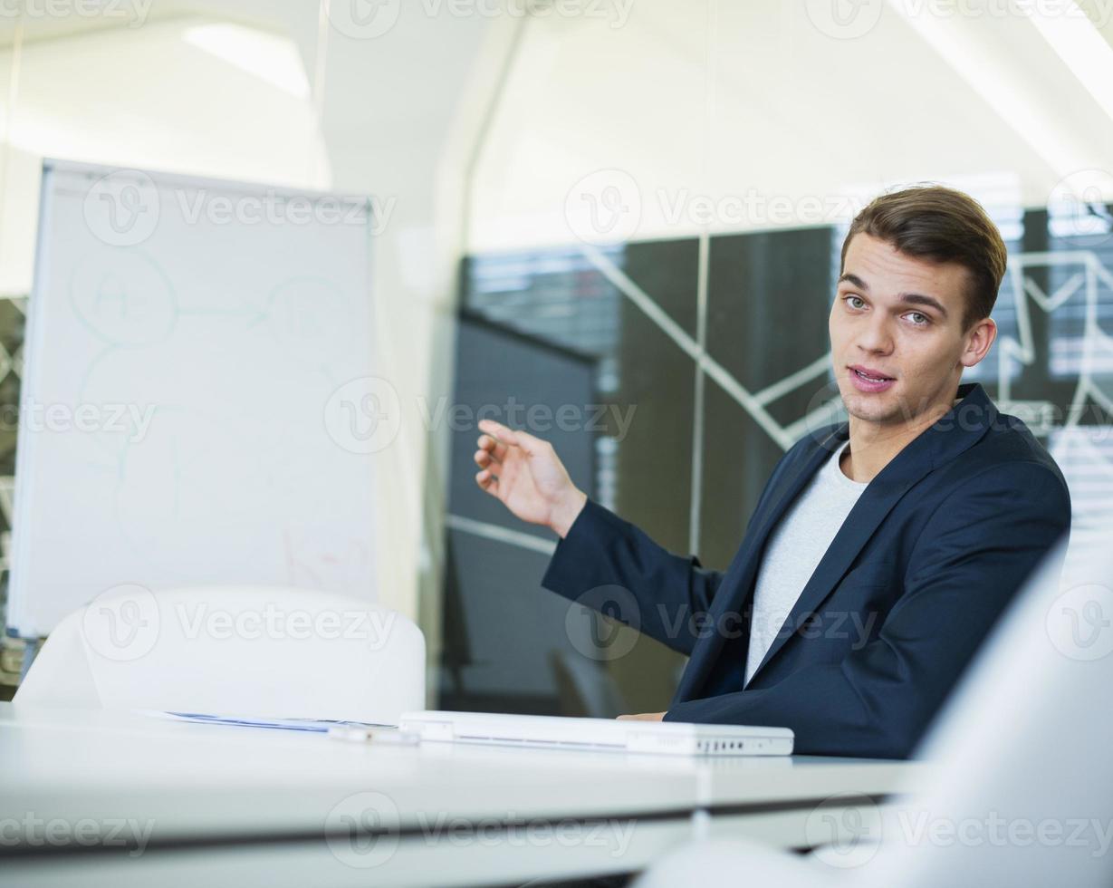 Portrait of young businessman giving presentation at conference table photo