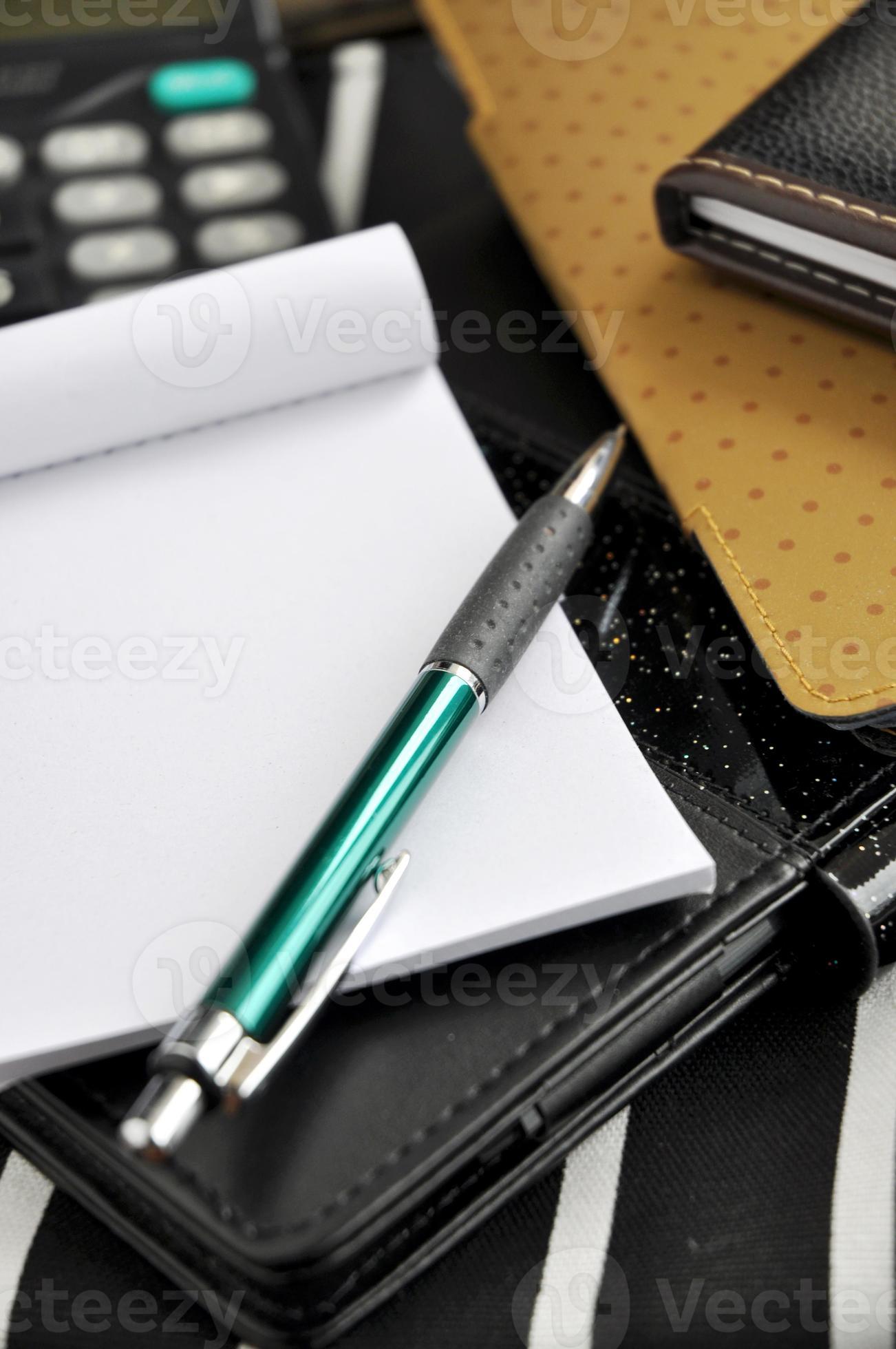 pluma puesta en el bloc de notas en blanco foto