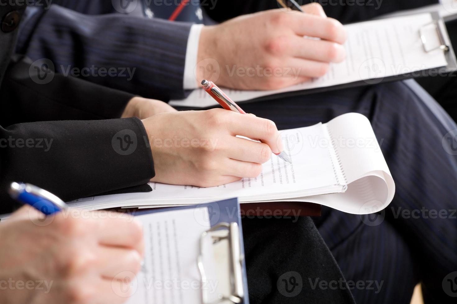 Hombres tomando notas en una conferencia de trabajo con lápiz y papel foto