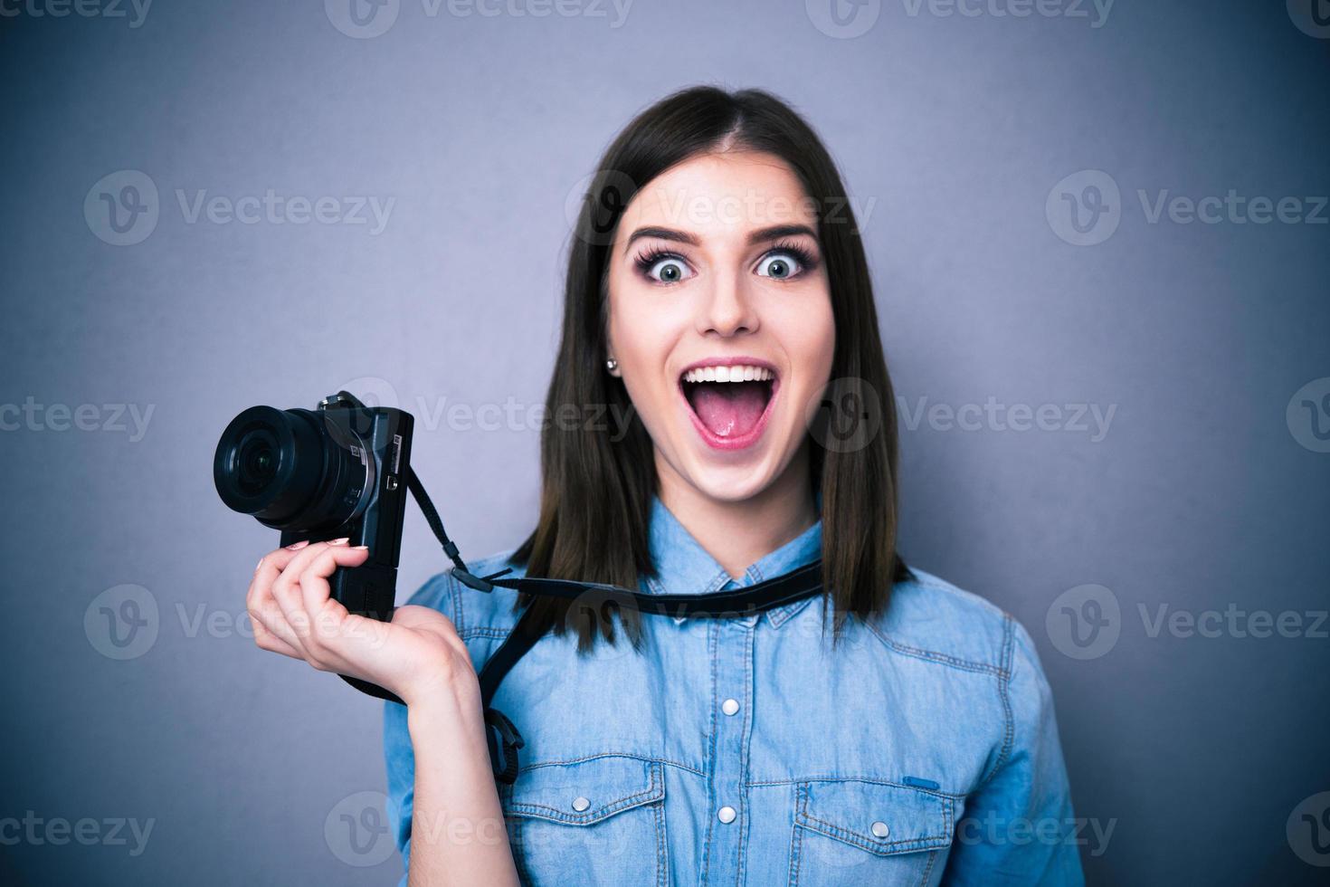 Amazed young pretty woman holding camera photo