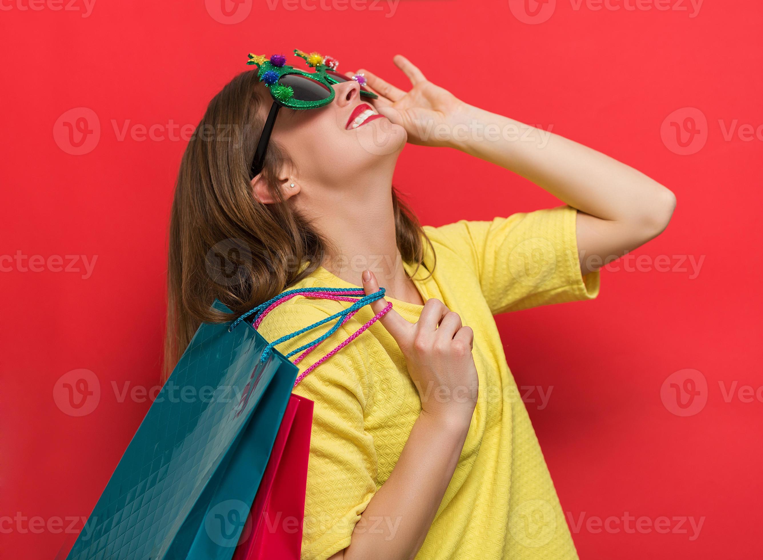 mujer con gafas de fiesta de navidad y bolsas de compras foto