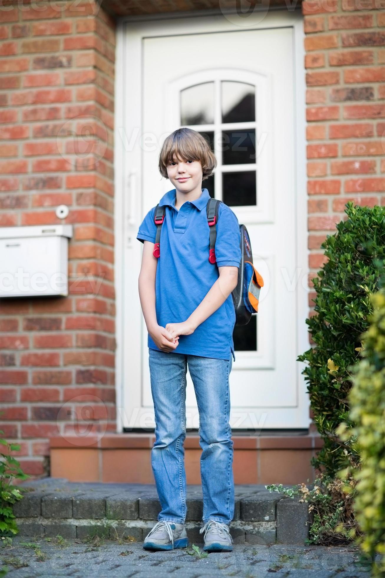 lindo chico estudiante saliendo de casa para el primer día escolar foto
