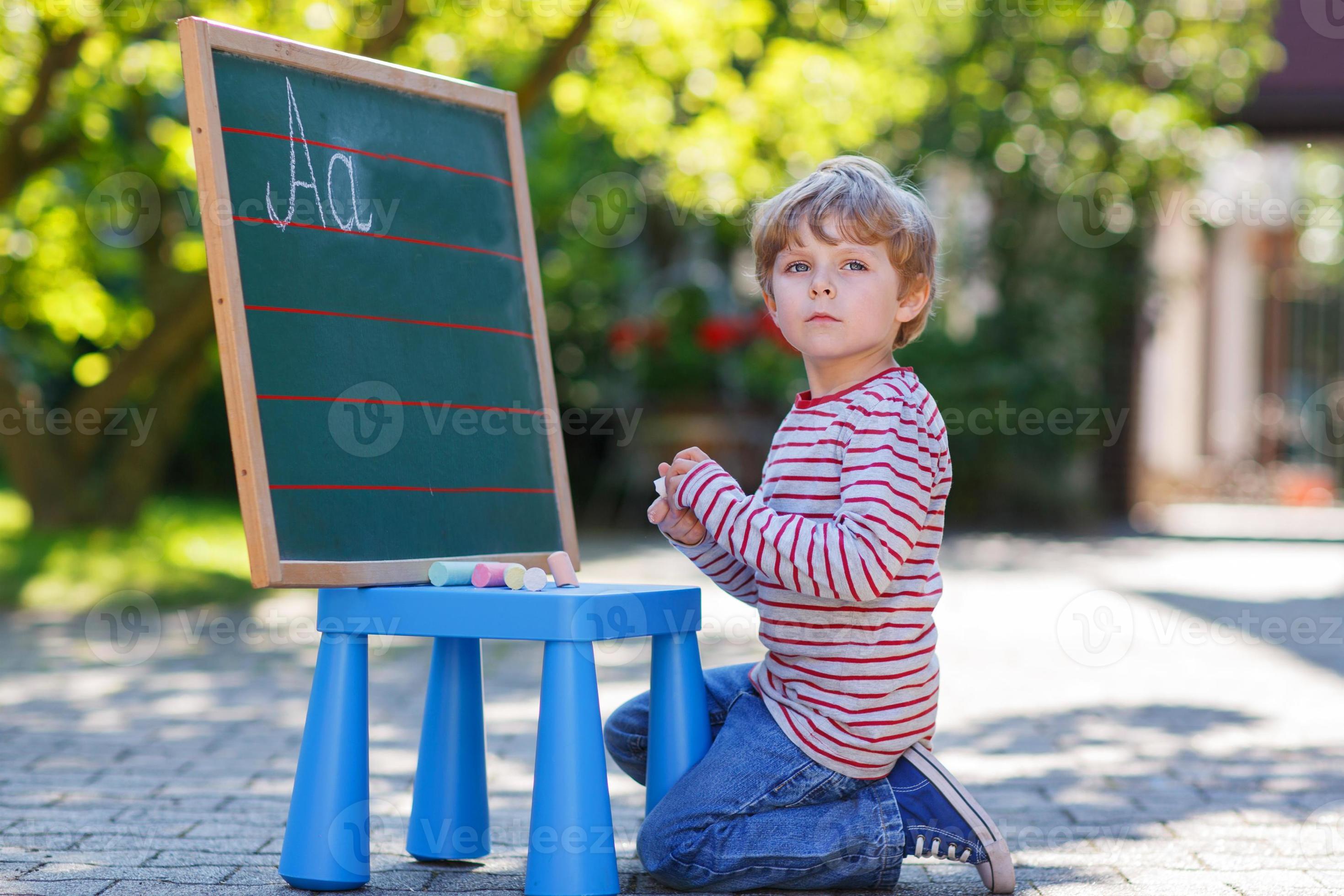 niño pequeño en la pizarra practicando matemáticas foto