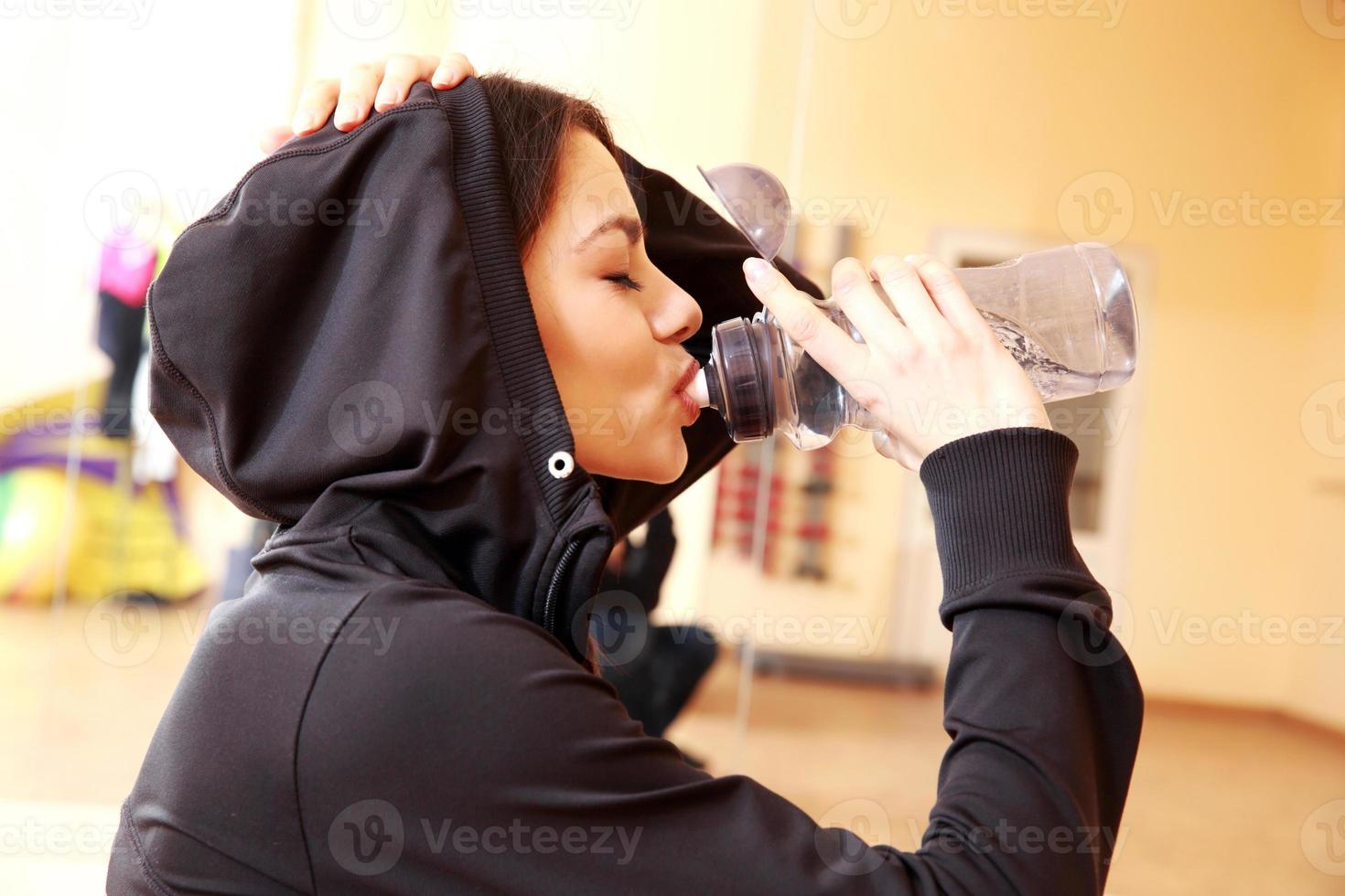 Young fit woman drinking water photo
