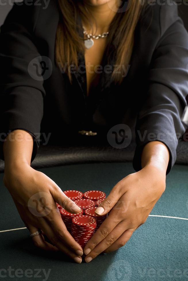Mujer recogiendo montones de fichas de juego en la mesa, sección media foto