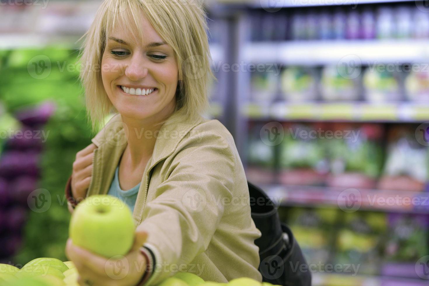 Mujer elegir manzana verde de la pantalla en el supermercado (differen foto