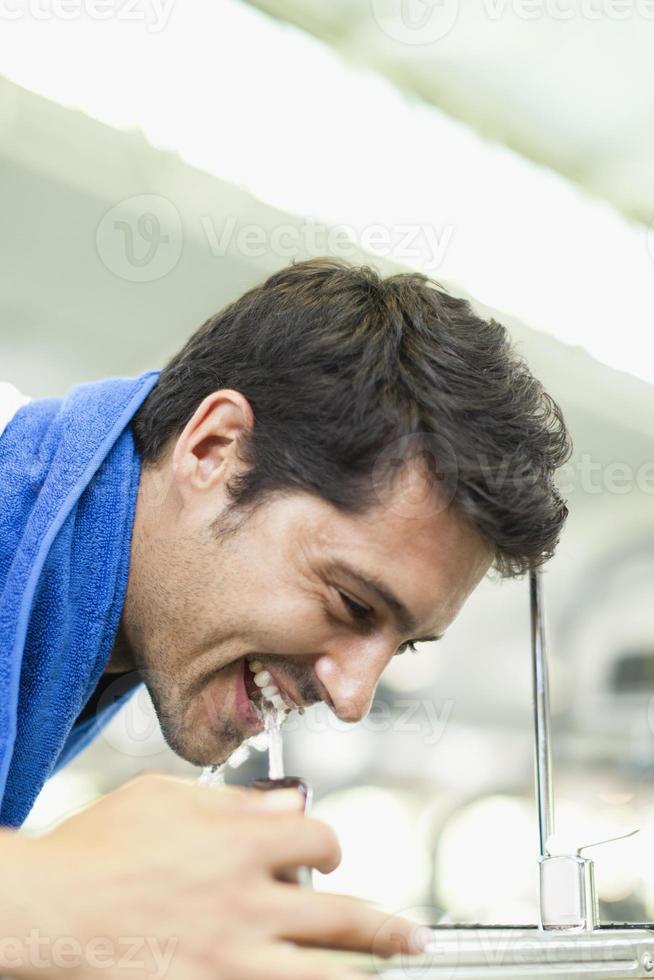 Man drinking from water fountain photo