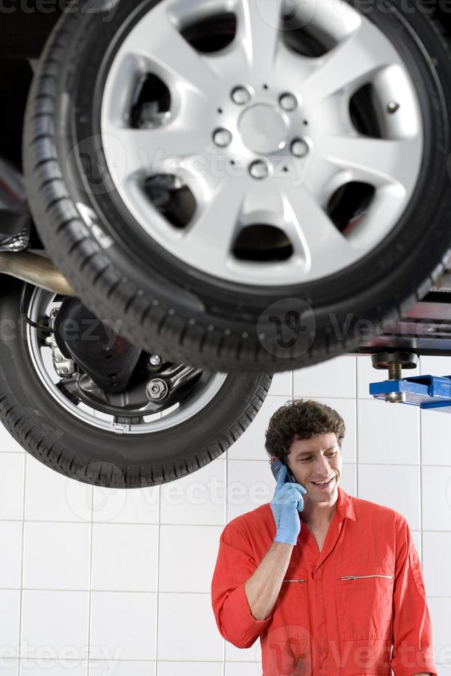 Male car mechanic using mobile phone photo