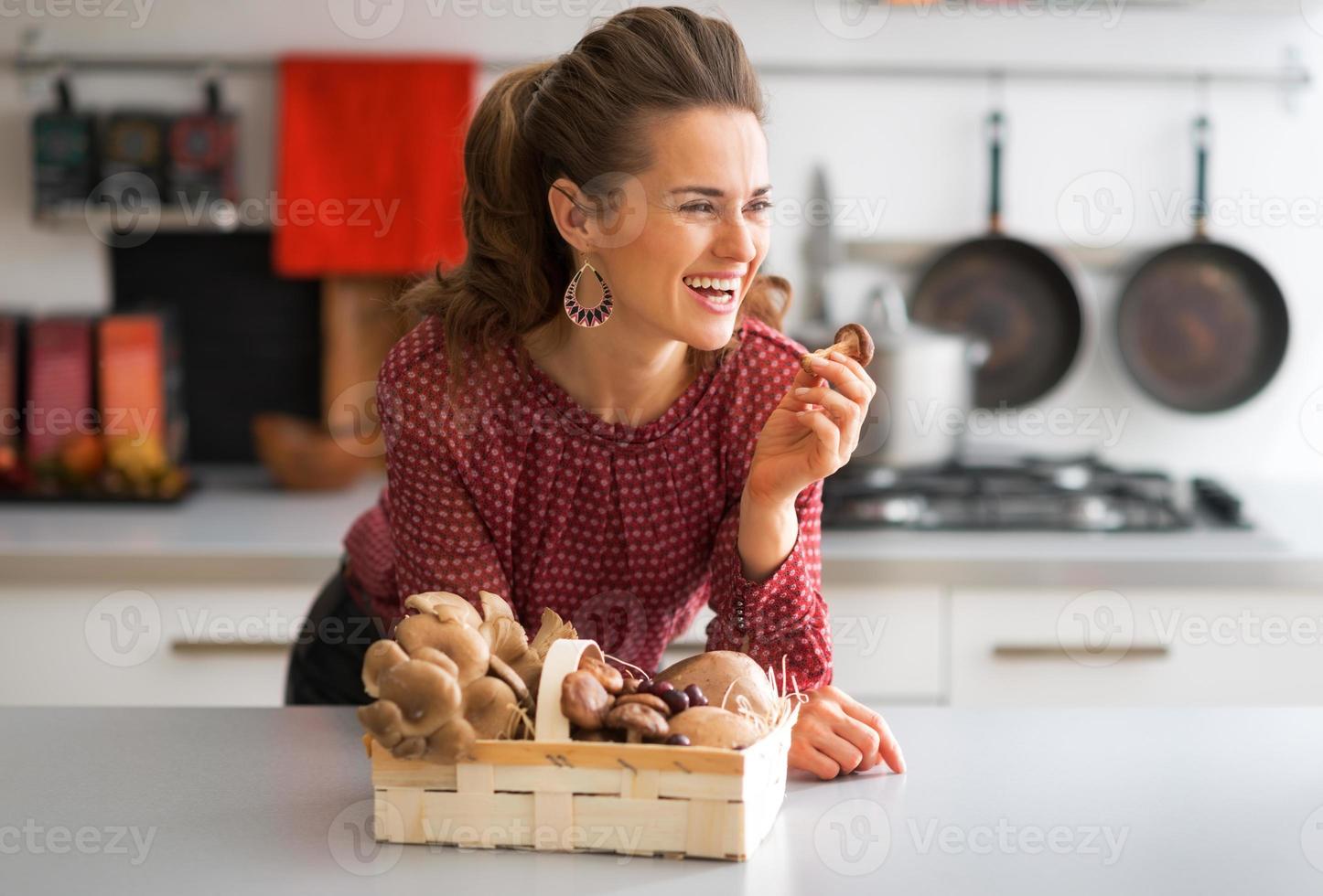 Portrait of happy young housewife with mushrooms in kitchen photo