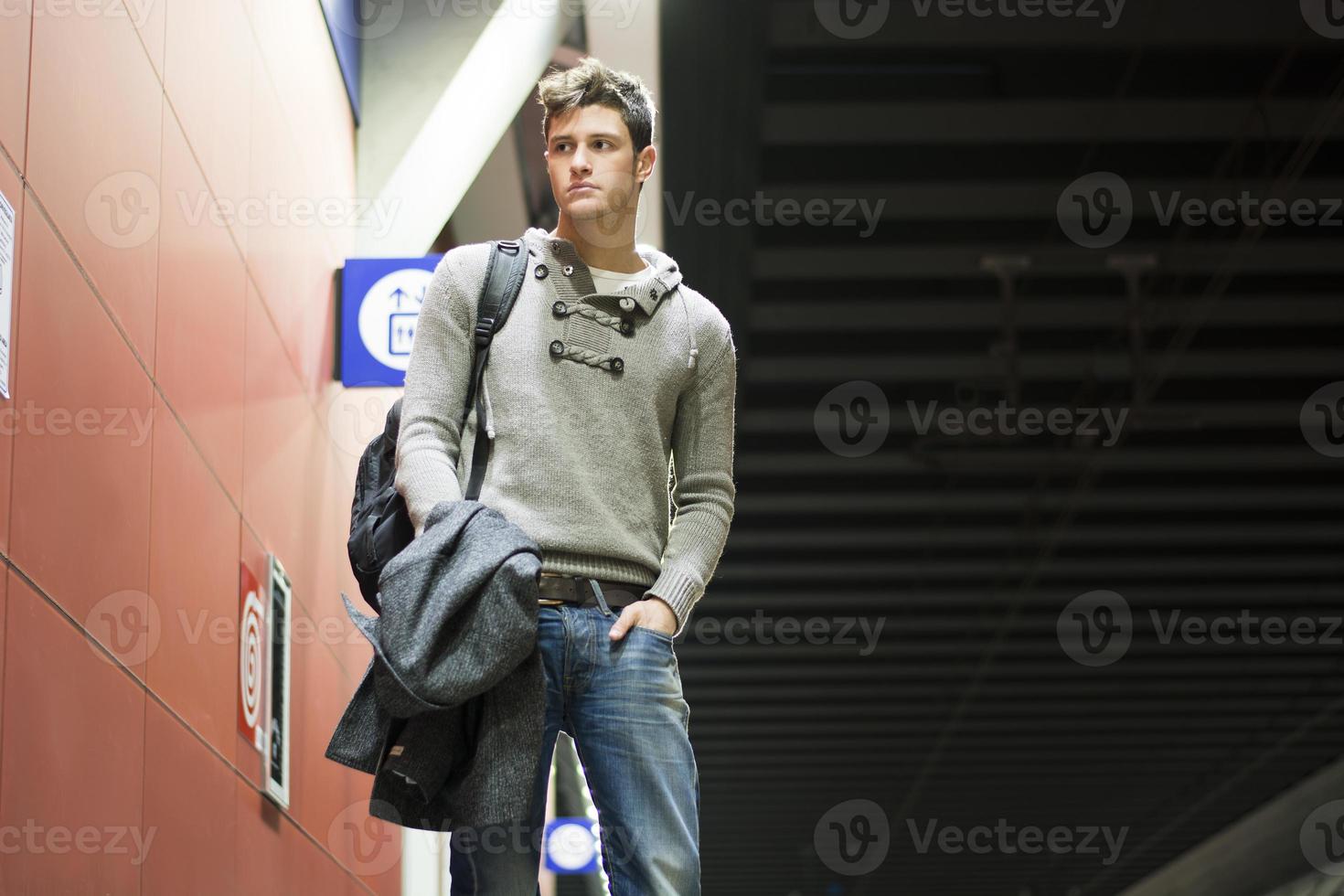 Handsome young man standing in train or subway station photo