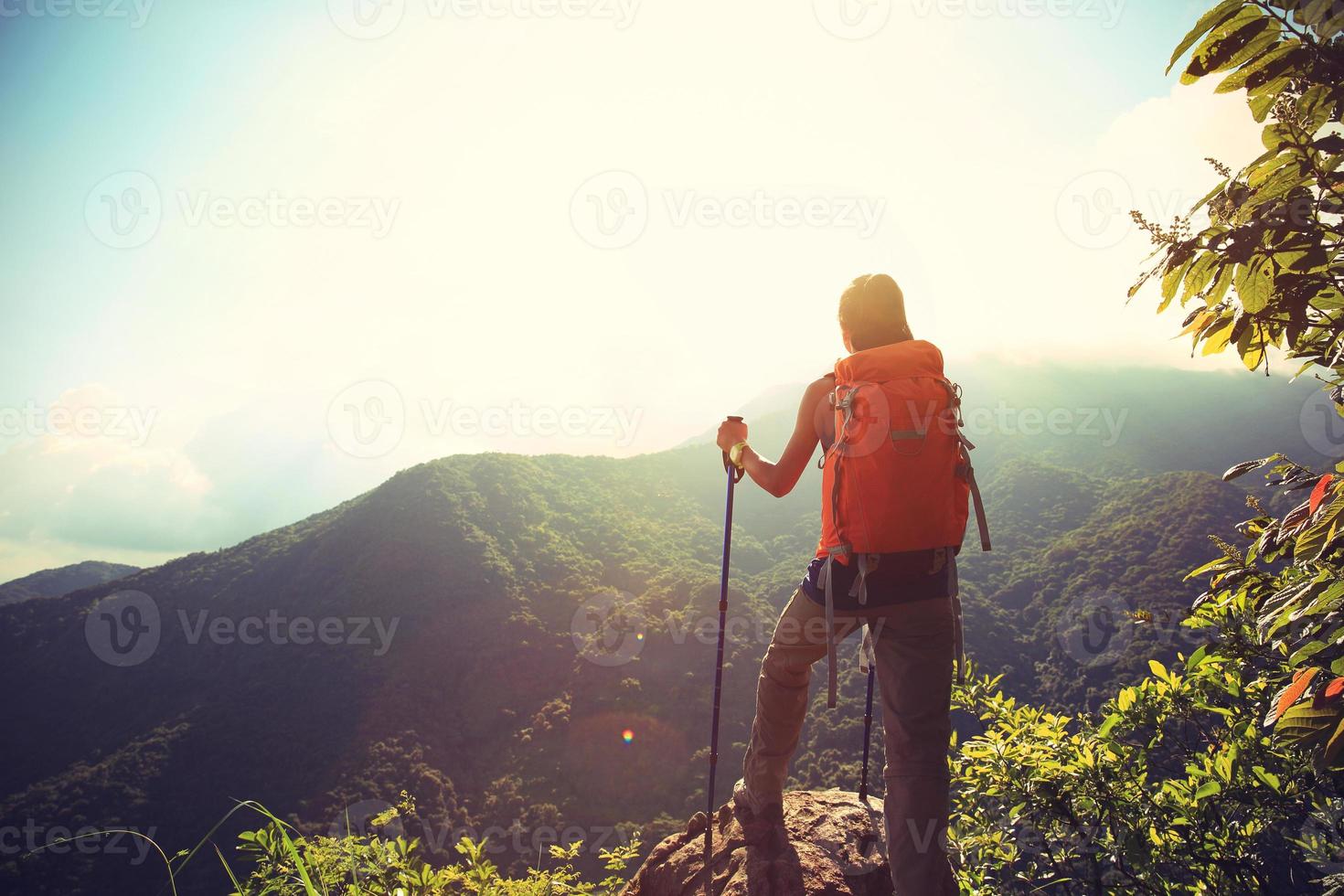 cheering woman hiker climbing to mountain peak photo