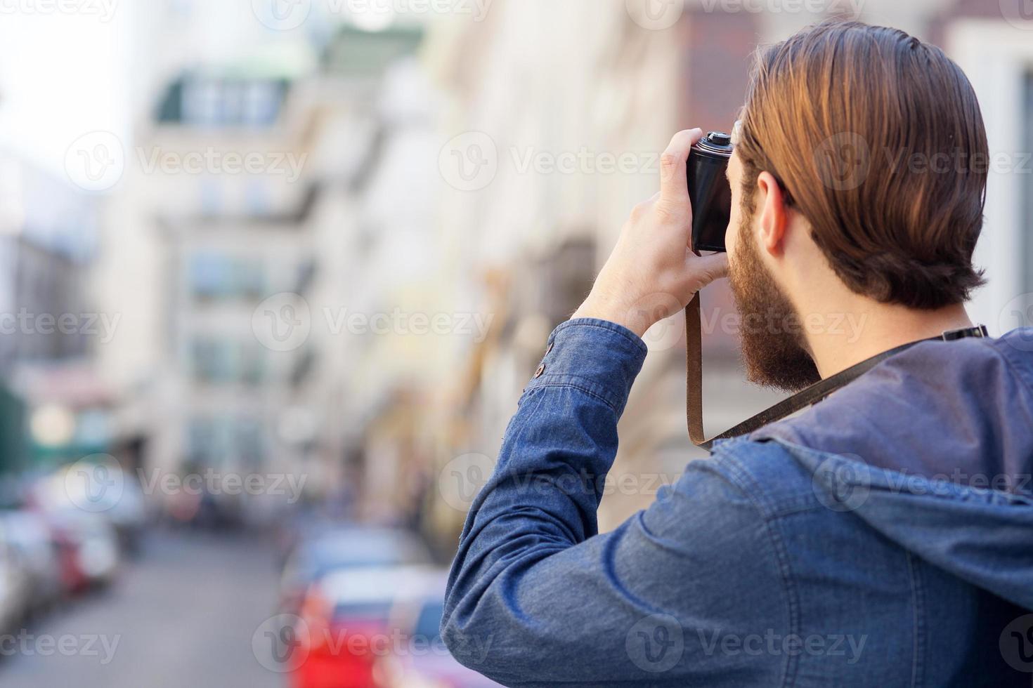 Cheerful bearded photographer is making photos of town