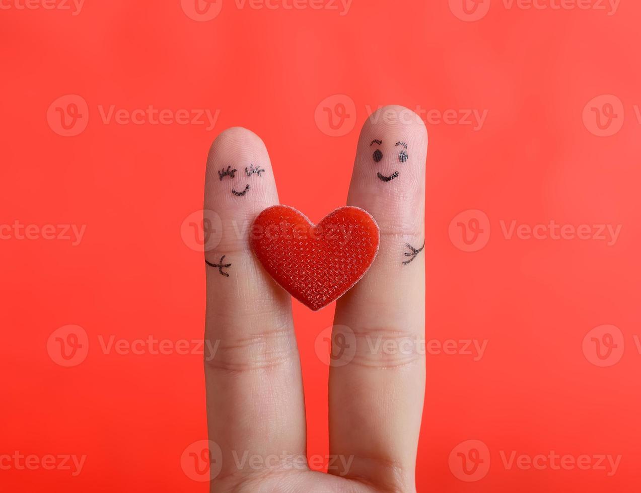 sonriente dedo pintado sobre fondo rojo, concepto de San Valentín. foto