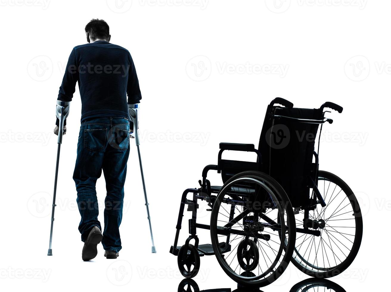 injured man  with crutches walking away from wheelchair silhouette photo