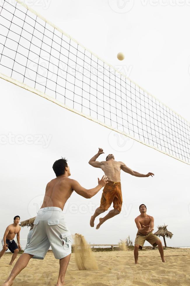 amigos varones jugando voleibol en la playa foto