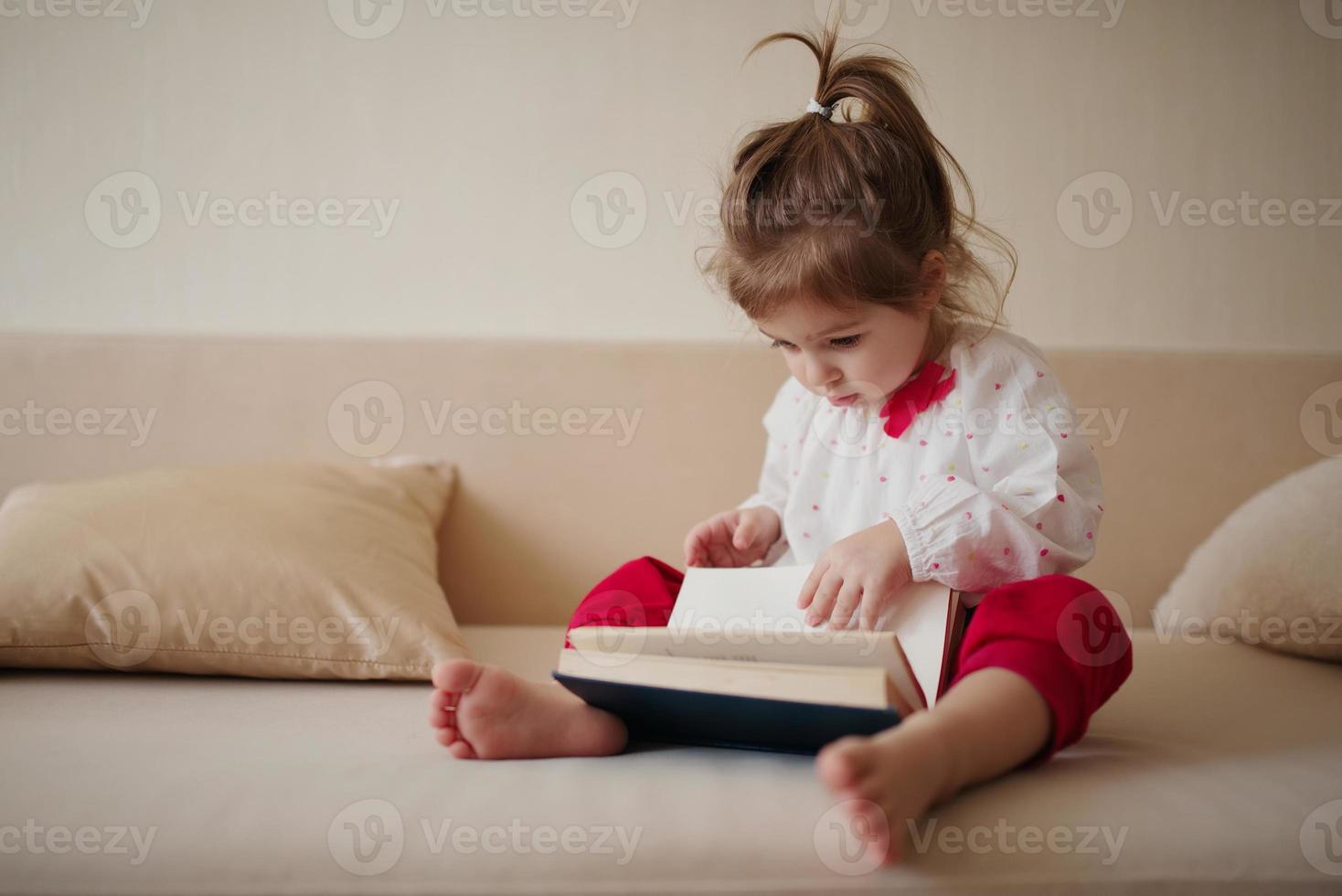 little girl reading book at home photo