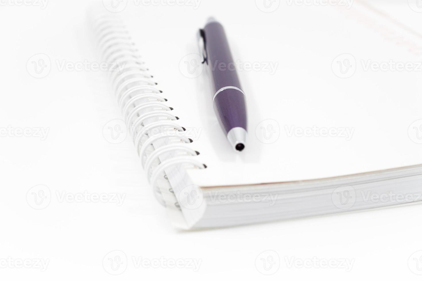 Cuaderno espiral con bolígrafo aislado sobre fondo blanco. foto