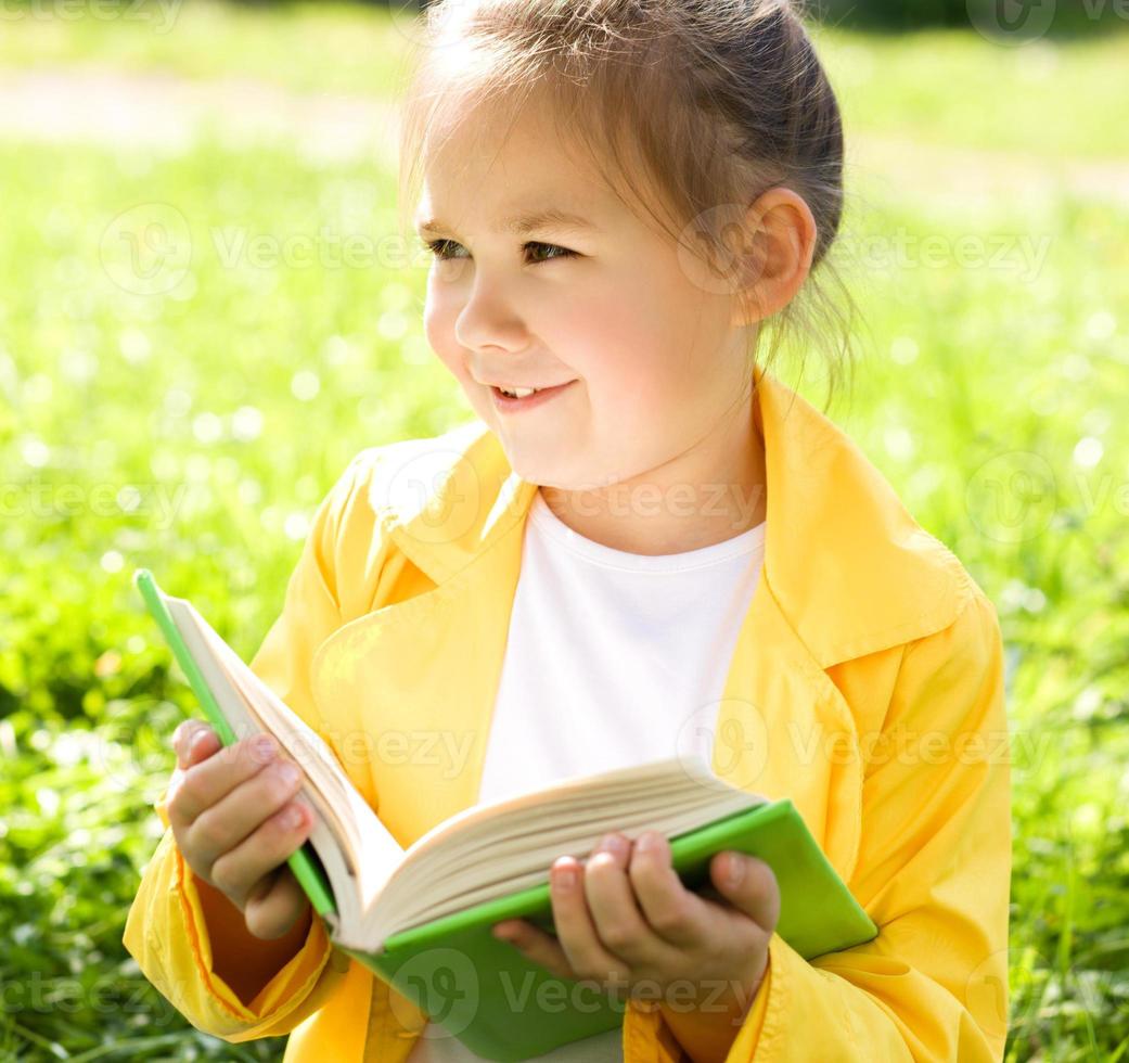 niña está leyendo un libro al aire libre foto