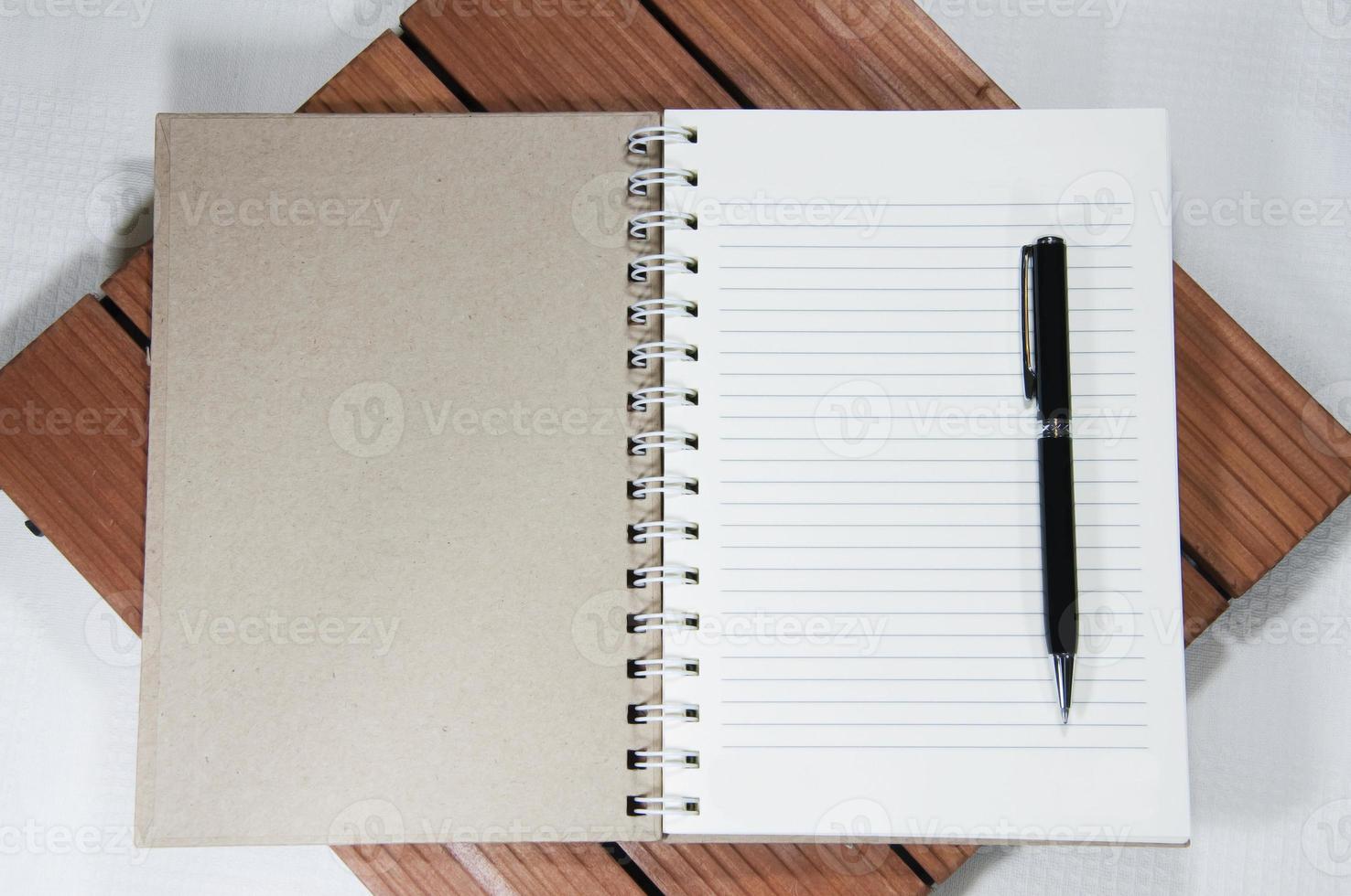 cuaderno blanco en blanco y bolígrafo sobre la madera foto