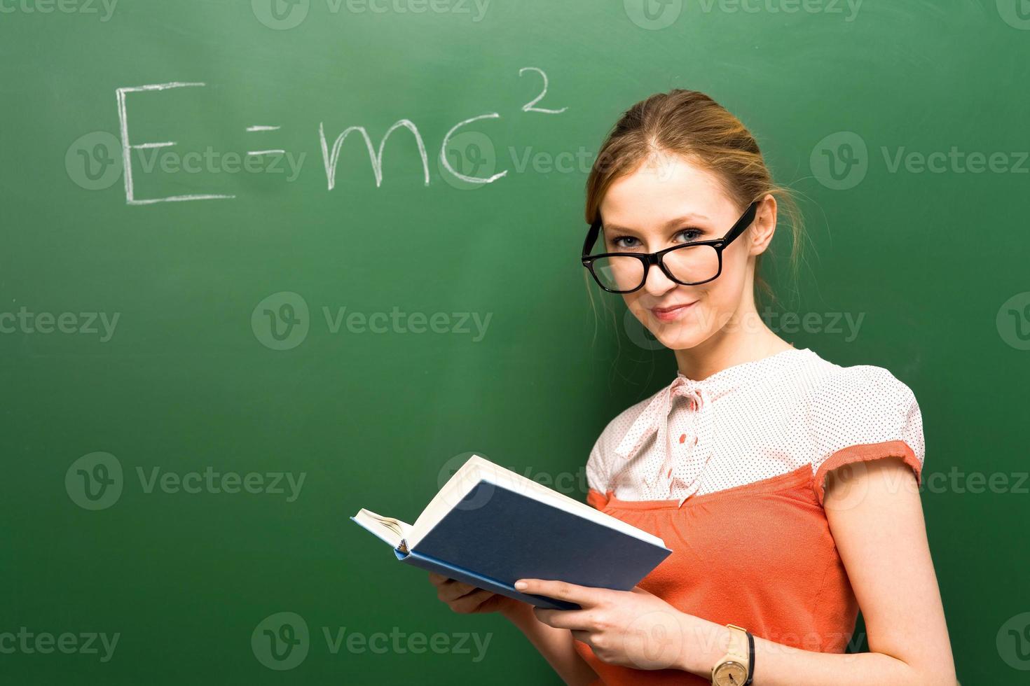 Student standing by chalkboard with e=mc2 photo