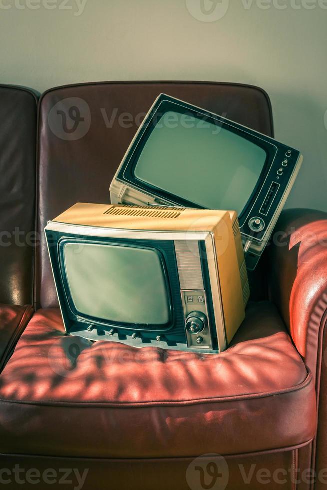 dos televisores antiguos en sofá rojo foto