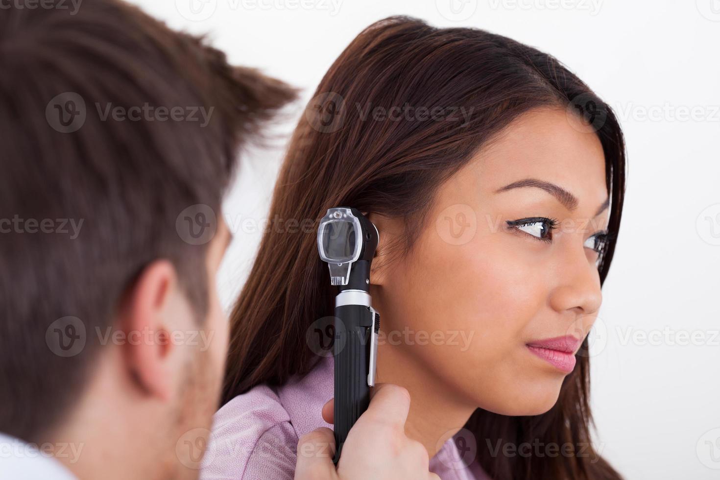 Doctor examinando el oído del paciente con otoscopio foto