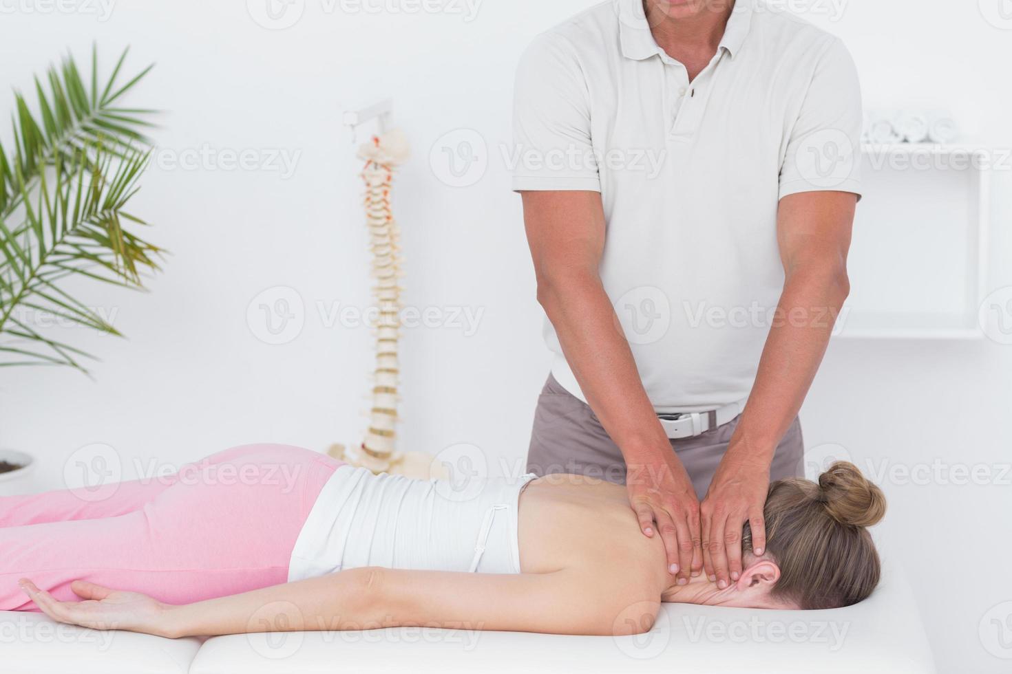 Physiotherapist doing neck massage to his patient photo