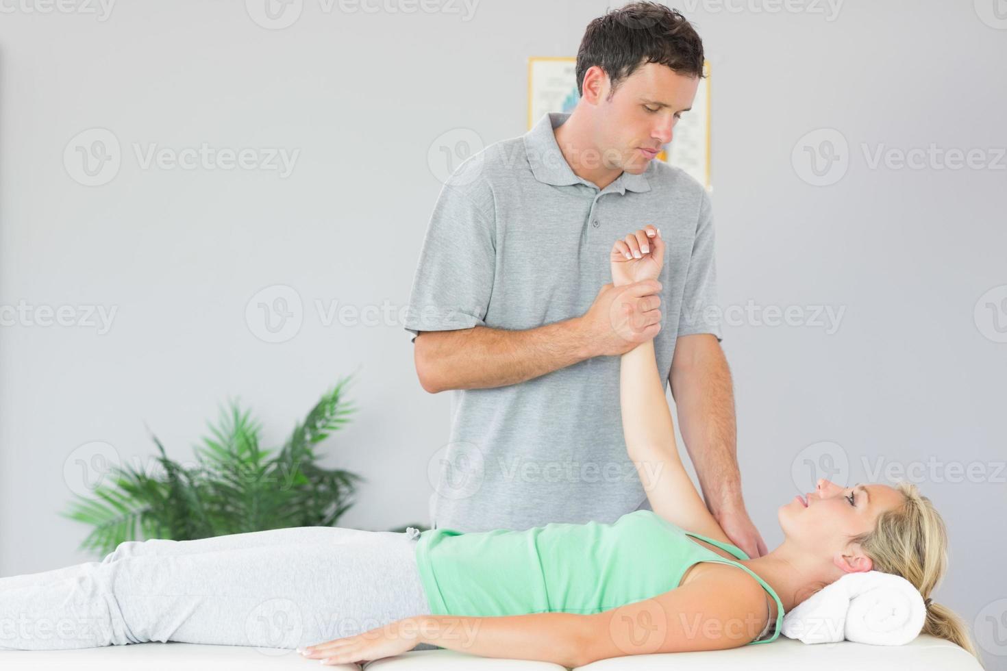 Handsome physiotherapist treating patients shoulder photo