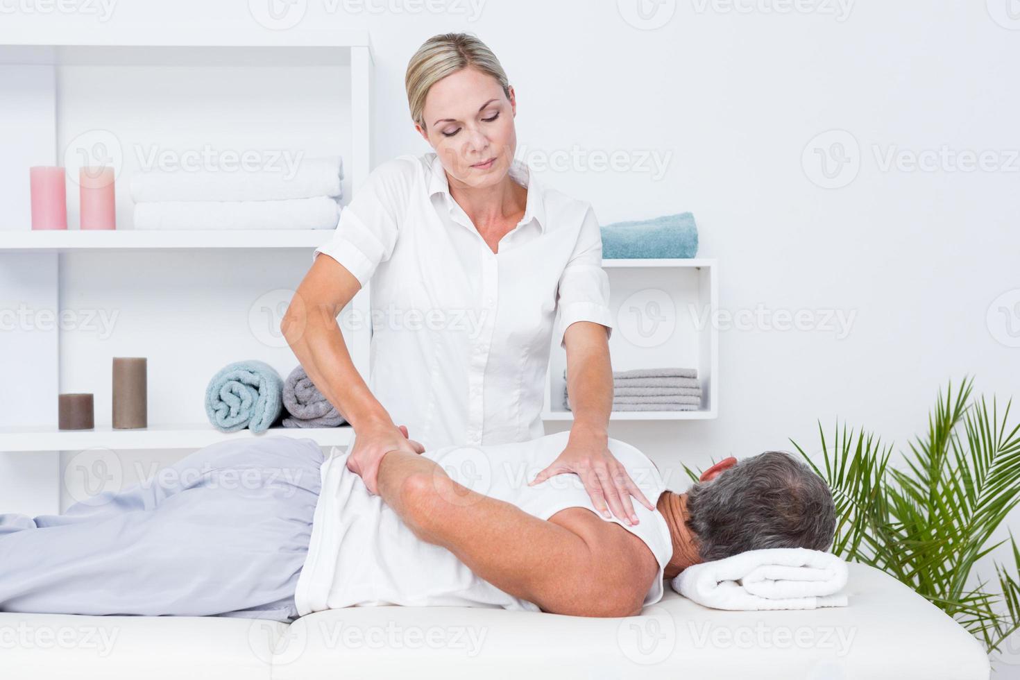 Physiotherapist doing shoulder massage to her patient photo