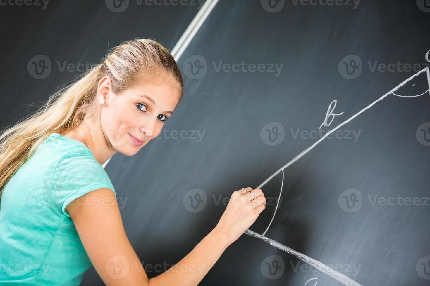 Pretty young teacher writing on the blackboard photo