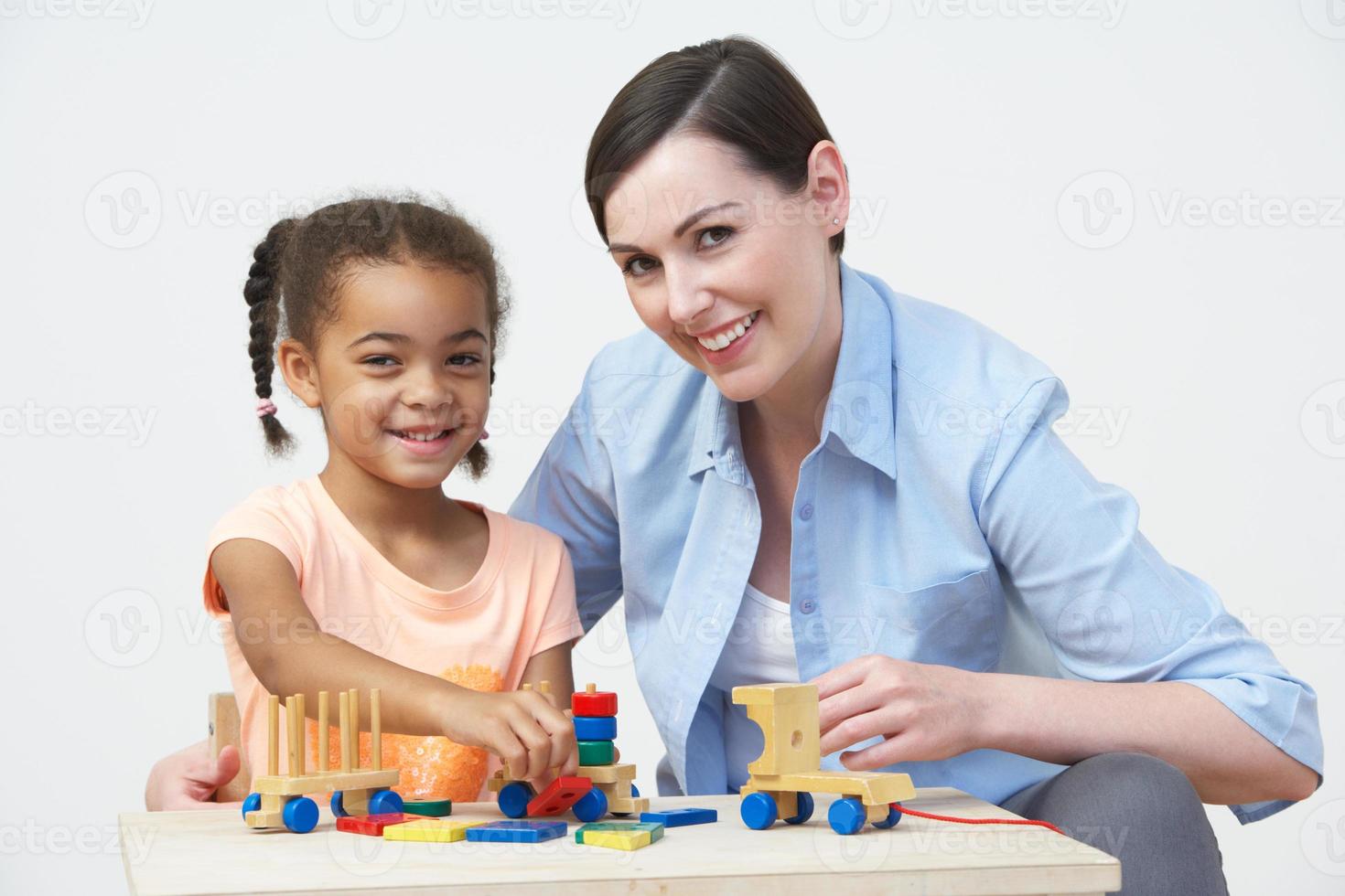 Profesor y alumno de preescolar jugando con casa de madera foto