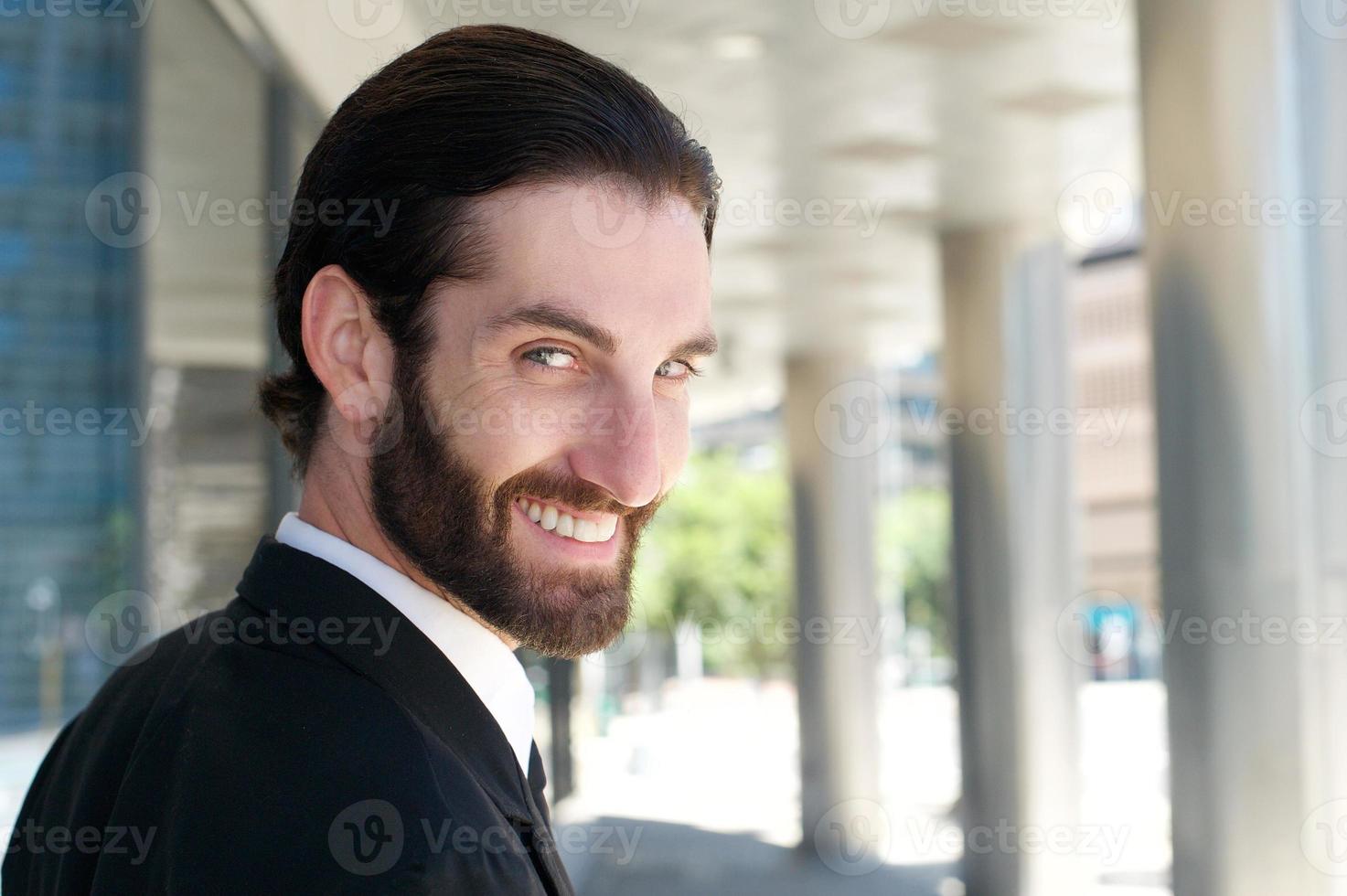 apuesto joven con barba sonriendo afuera foto