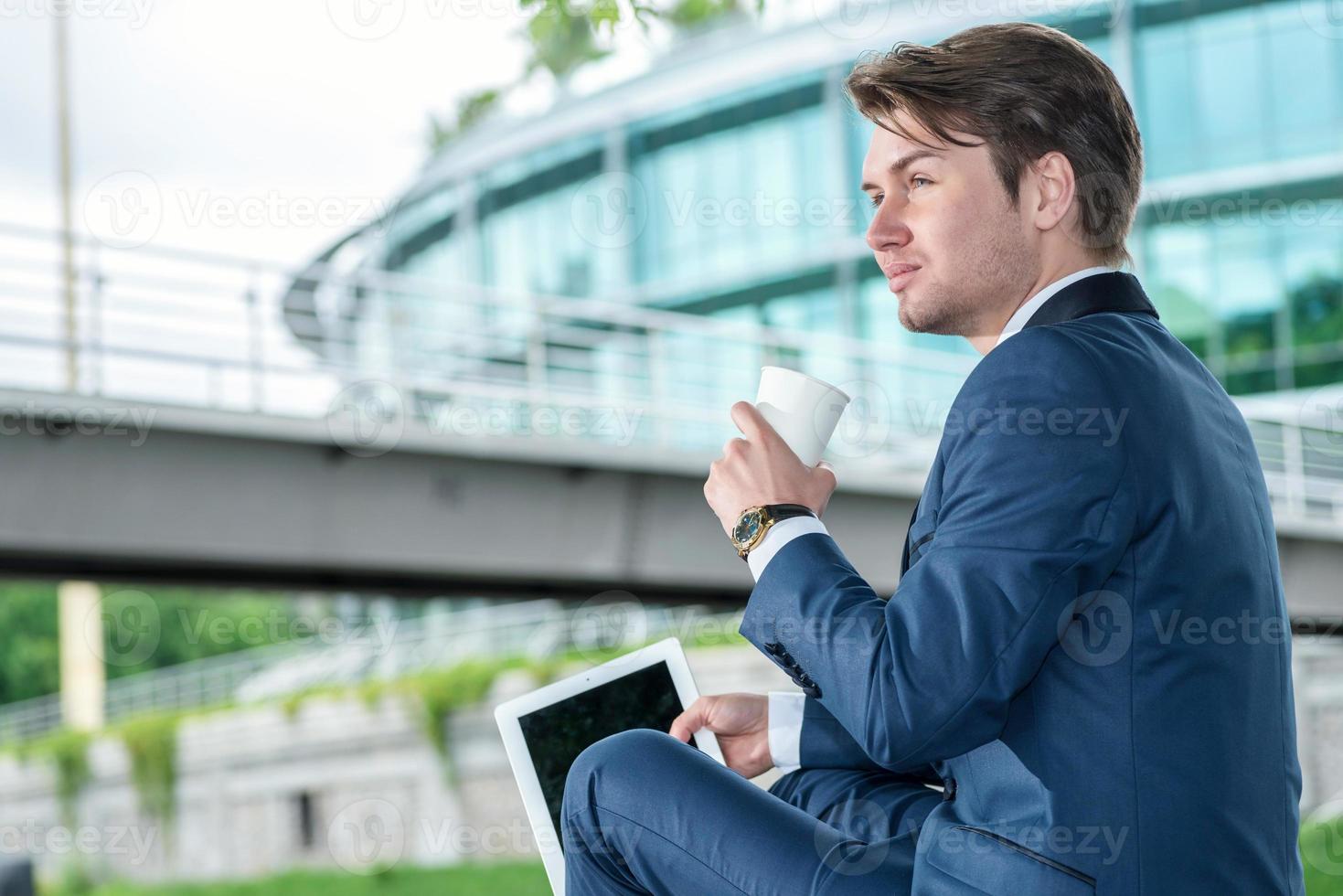 empresario sentado al aire libre y tomando café y trabajando el foto