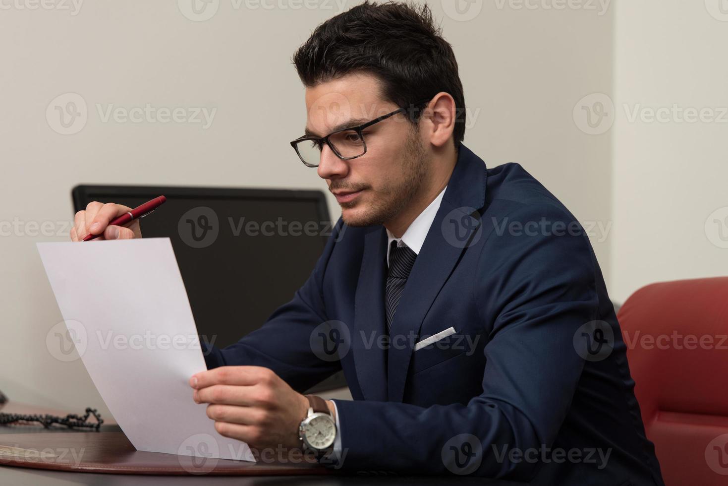 joven empresario en la oficina mirando el papel foto