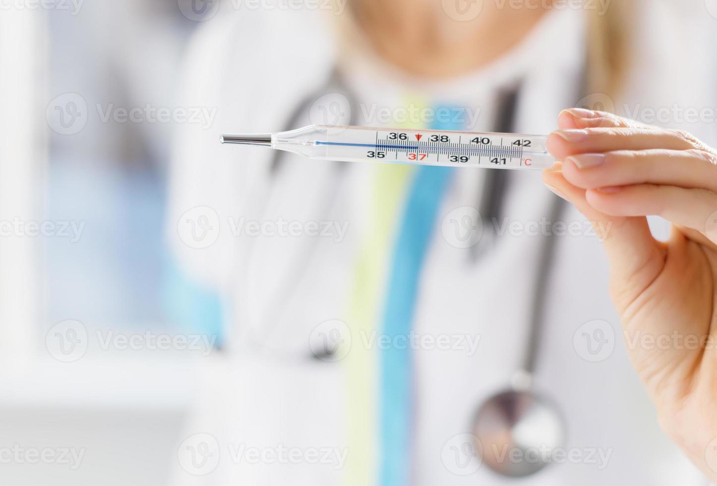 Doctor holding thermometer photo