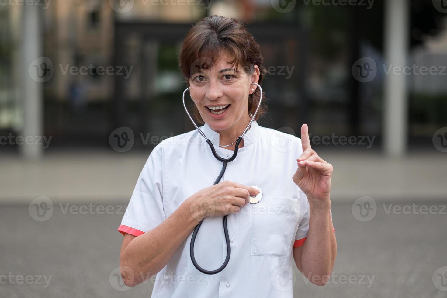 Smiling cardiologist listening to her heart photo